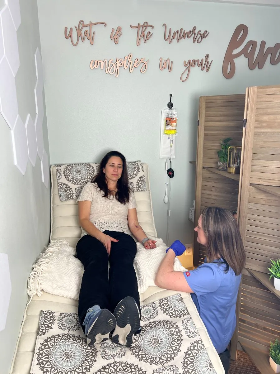 A nurse checks in on a client receiving an infusion in the Infusion Vibes treatment room